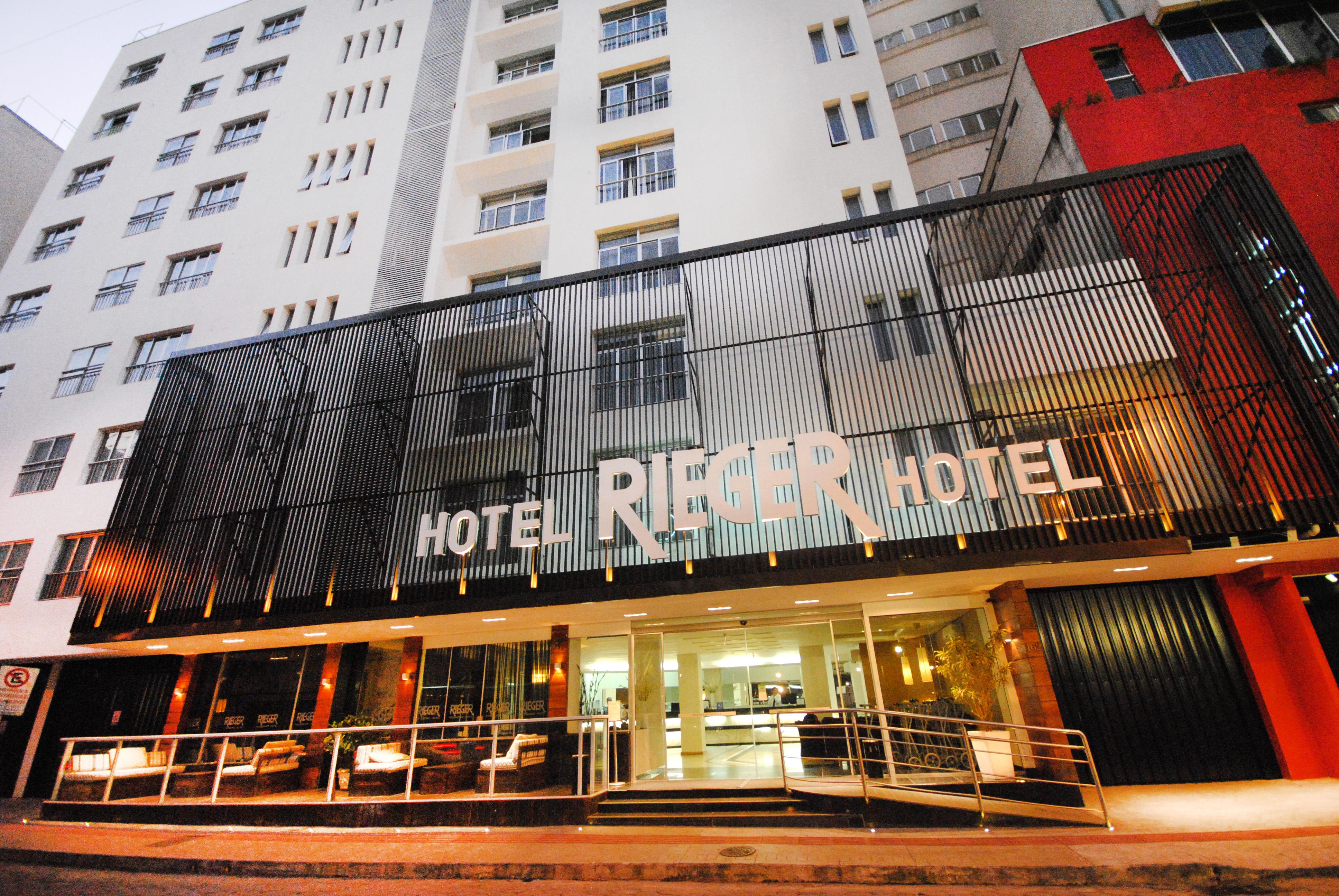 Entrada iluminada do Hotel Rieger com fachada moderna e prédio alto